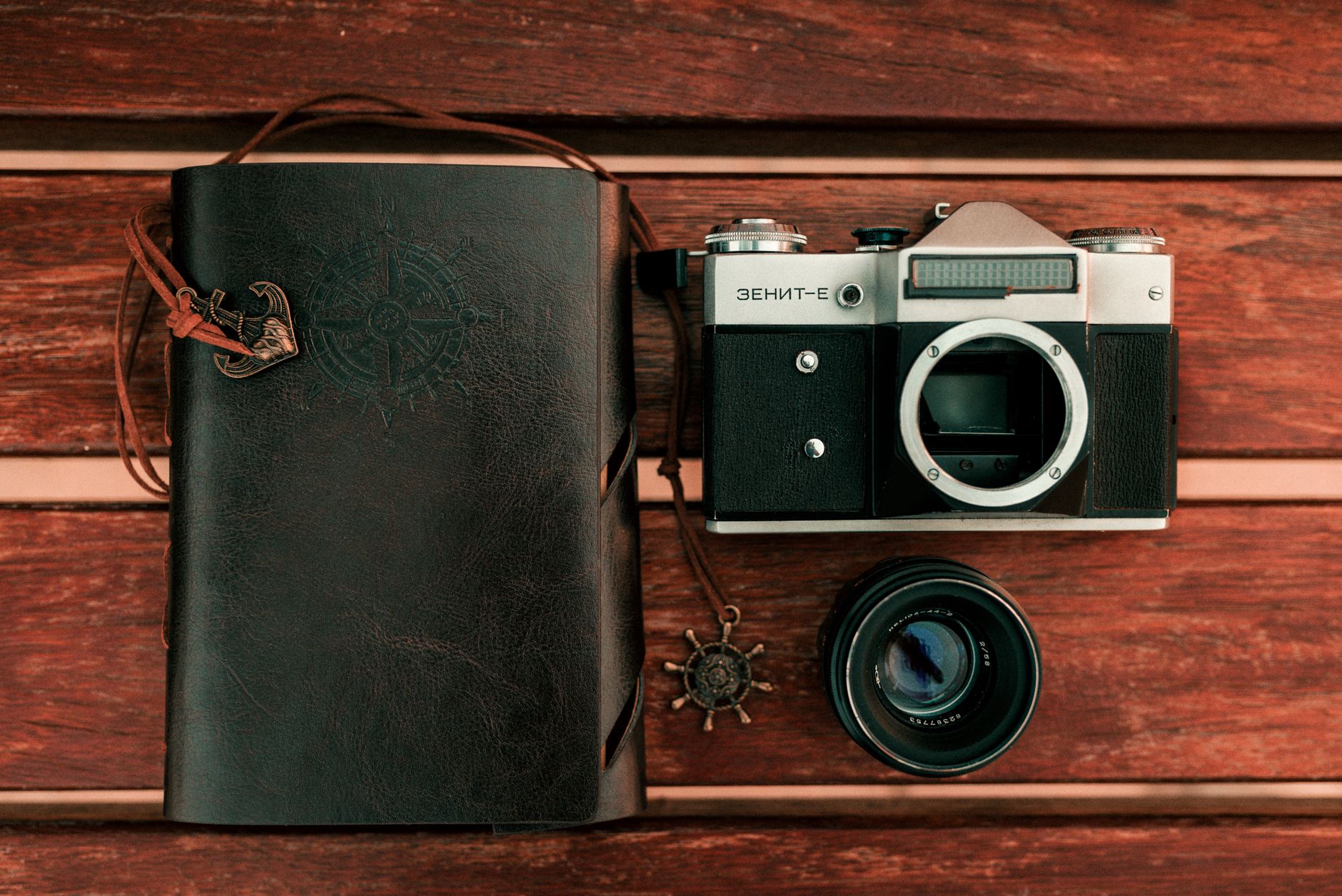 Travel journal and vintage compass on wooden table